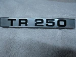 Triumph TR250 Hood Fender Badge Nos 621864. Fixed Price $80.00.